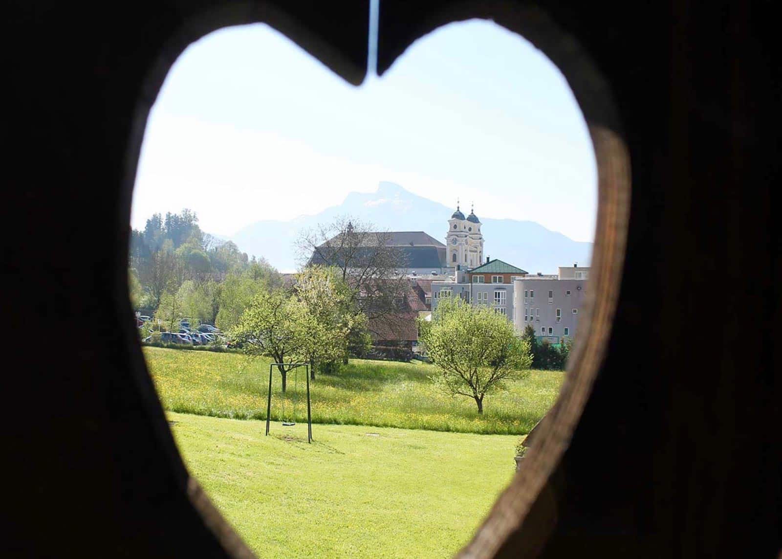 Ein Holzherz bei dem man durchsehen kann und die Stadt sieht
